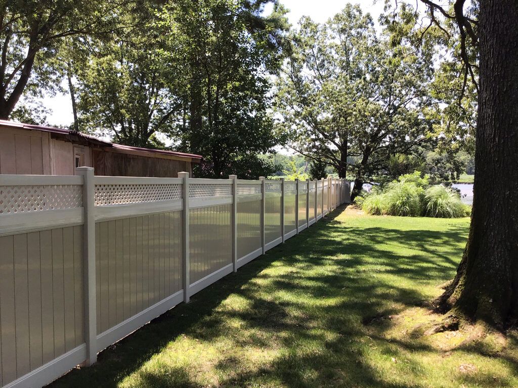 A vinyl privacy fence on a sunny waterside property showing that the fence would keep any pets safely on the property.