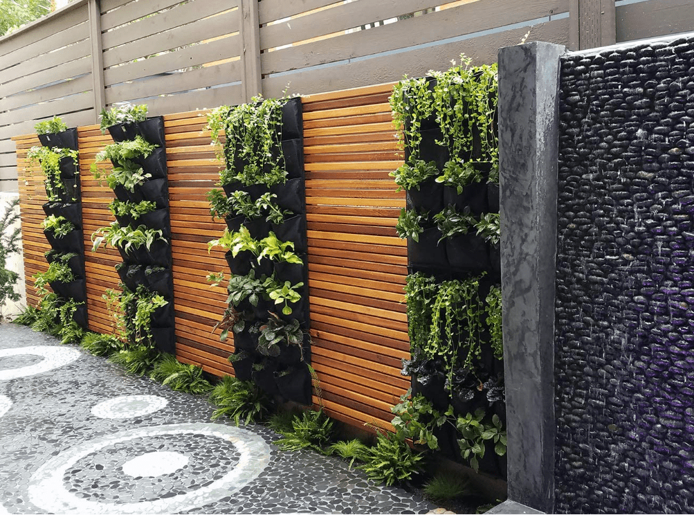 a hanging garden in a backyard in front of a vinyl privacy fence.