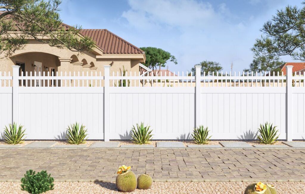 a vinyl privacy fence along a stone brick pathway in an arid climate. The vinyl fence has spear topped pickets.