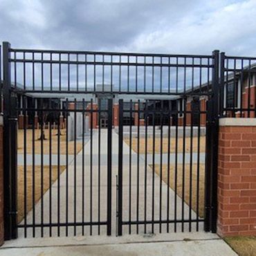 Custom black aluminum gate fencing built on retaining wall